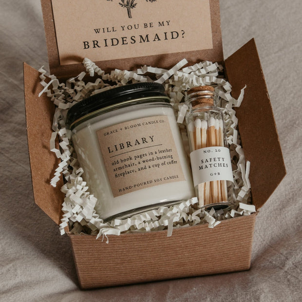 Treat your favorite bookish friends with this dark academia bridesmaid proposal gift box! It contains everything they need to set the mood as they get lost in a good book. With a scented candle in a literary theme, a decorative glass bottle of white-tipped matches, and a custom-designed "Will you be my bridesmaid" card that doubles as a bookmark, this is the perfect way to make your proposal extra special!