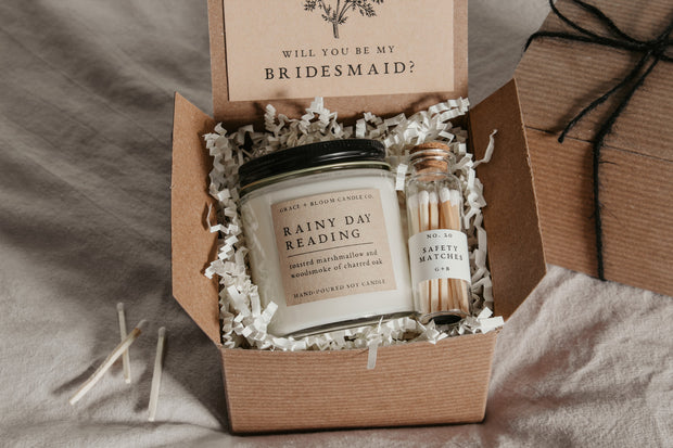 Treat your favorite bookish friends with this dark academia bridesmaid proposal gift box! It contains everything they need to set the mood as they get lost in a good book. With a scented candle in a literary theme, a decorative glass bottle of white-tipped matches, and a custom-designed "Will you be my bridesmaid" card that doubles as a bookmark, this is the perfect way to make your proposal extra special!
