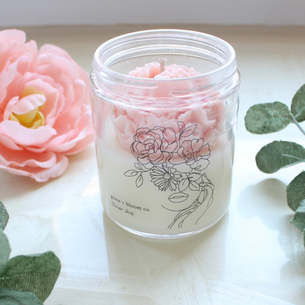 Bring the beauty of the outdoors into your home with a lovely flower candle in a fresh scent! The gorgeous peach-colored wax flower nestled inside and the whimsical hand-drawn flower lady on the label will elevate your decor with a bit of a cottagecore aesthetic